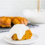 pumpkin bundt cake with cream cheese whipped cream on top on a white plate