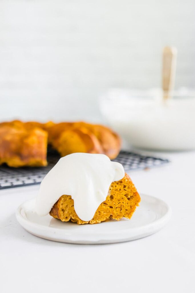 pumpkin bundt cake with cream cheese whipped cream on top on a white plate