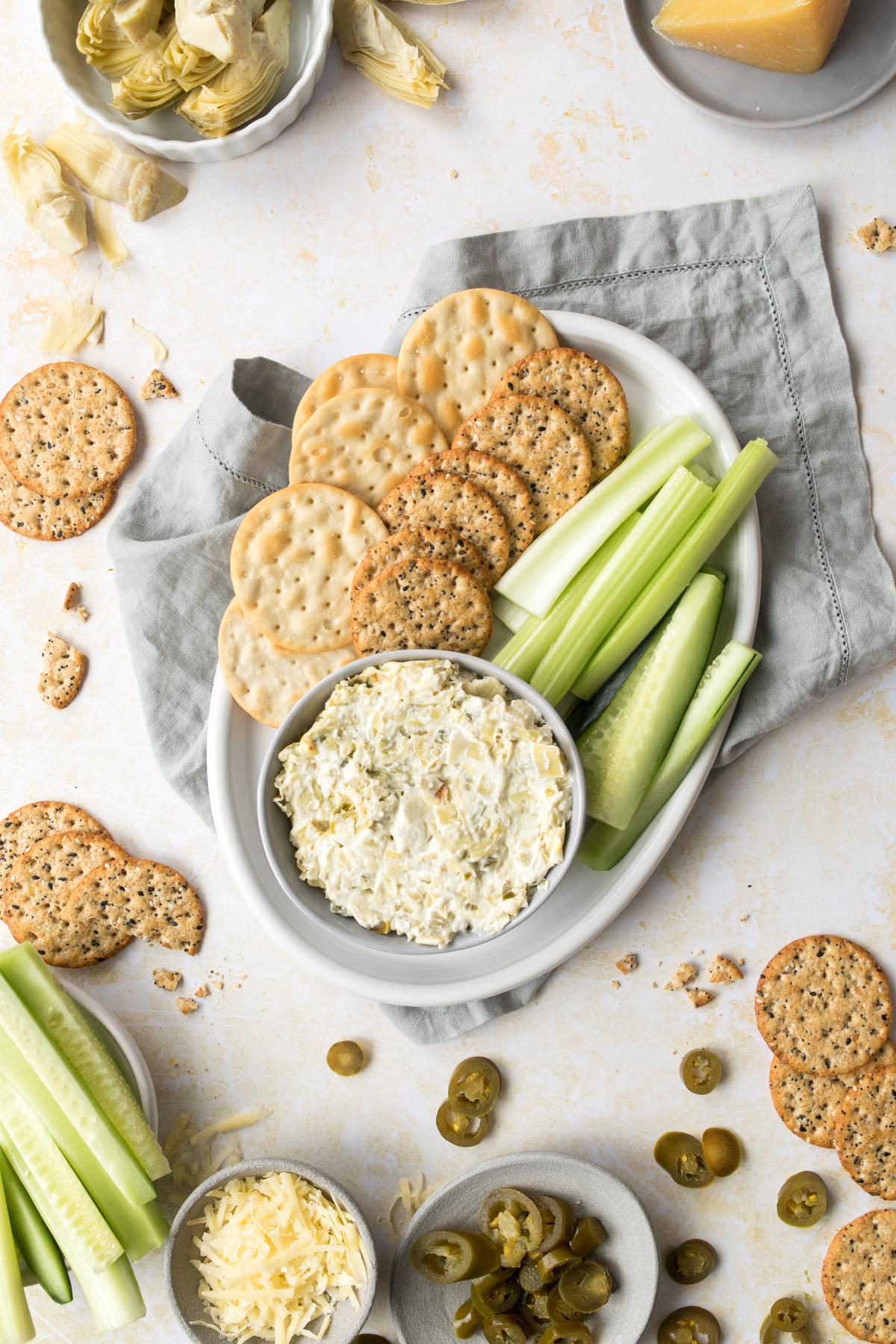 Jalapeno artichoke dip in bowl with vegetables and chips around