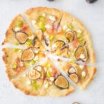 sliced fig and prosciutto pizza with figs next to it