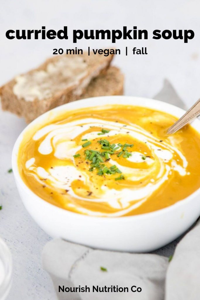 curry pumpkin soup with coconut milk swirl in a white bowl with bread in the background with text overlay