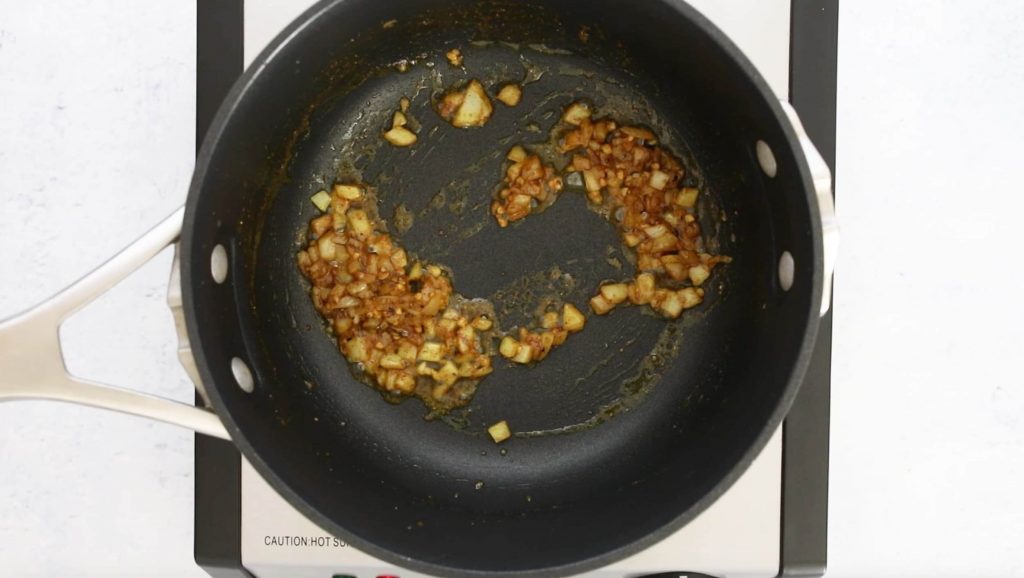 onions with curry powder cooking in a black pot