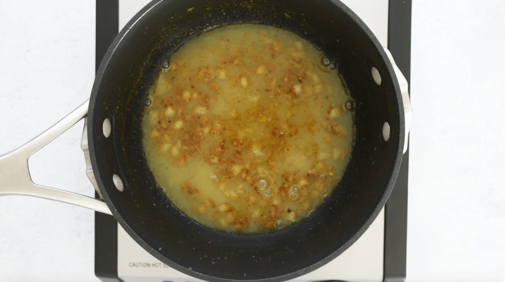 vegetable broth, onions, and curry powder cooking in a black pot