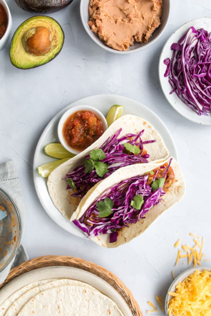 two tacos with red cabbage and cilantro on a plate