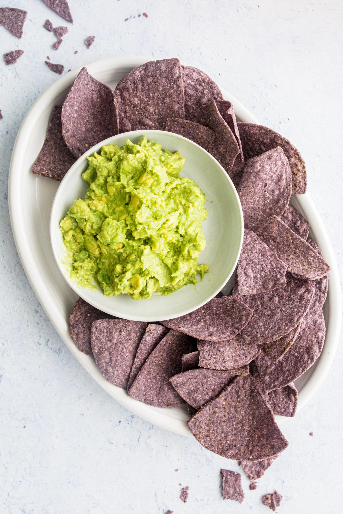 guacamole with blue corn tortillas on a white plate