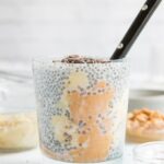chia pudding with peanut butter and chocolate chips on top in glass with ingredients in background