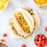 healthy breakfast tacos on a plate with ingredients surrounding them