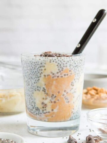 chia pudding with peanut butter and chocolate chips on top in glass with ingredients in background