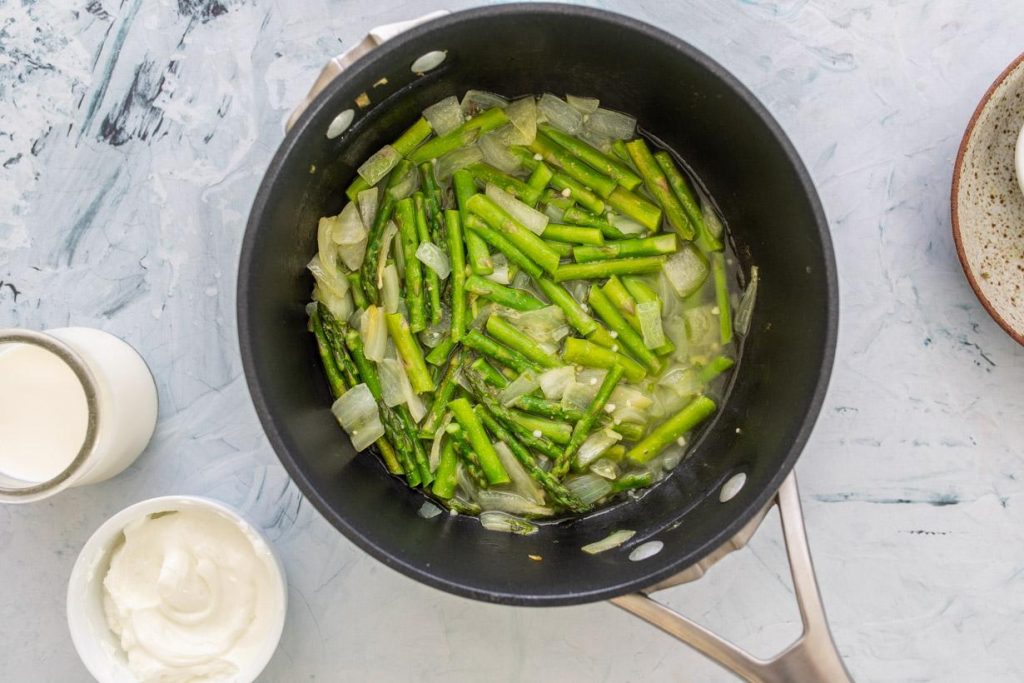 asparagus, onions, and broth in a pan
