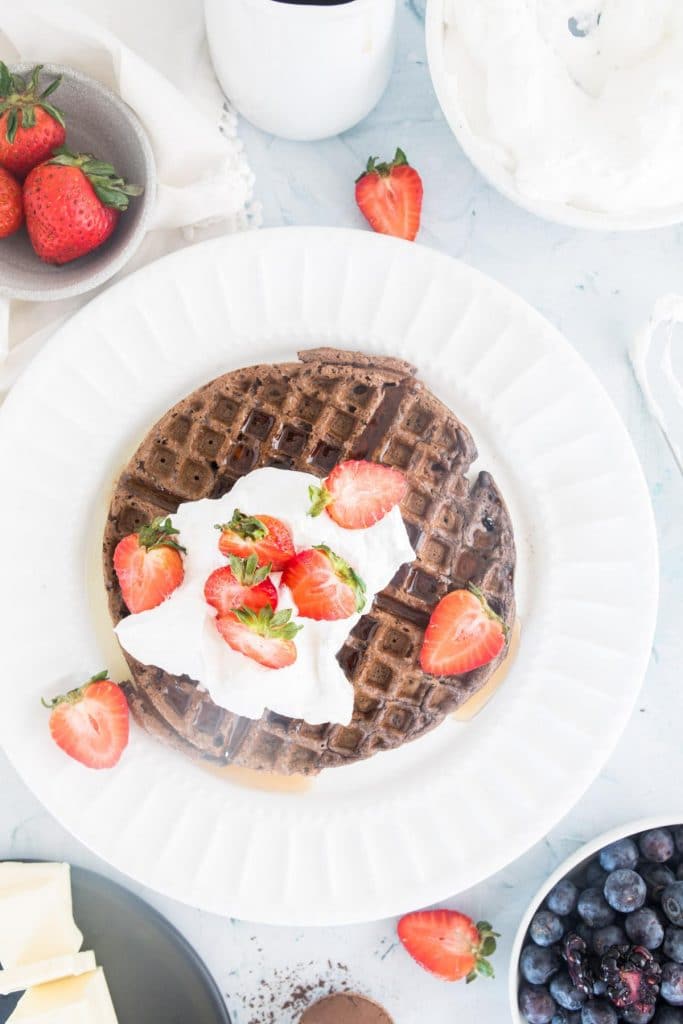 chocolate waffle with cream and strawberries on table