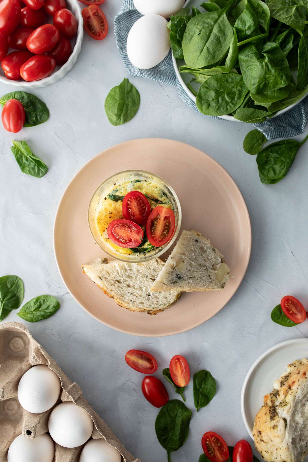 microwave egg bowl on a table with a fork, eggs, and spinach