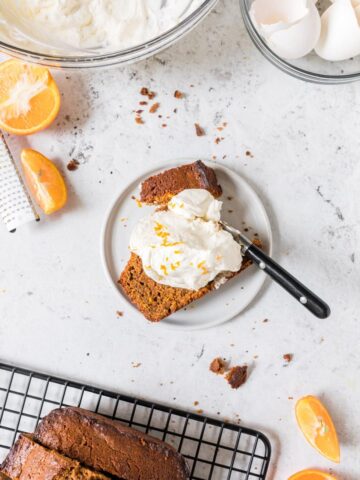 gingerbread poundcake with fresh whipped cream on white plate with more poundcake around it