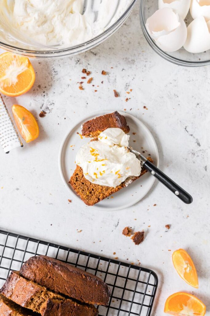 gingerbread poundcake with fresh whipped cream on white plate with more poundcake in background