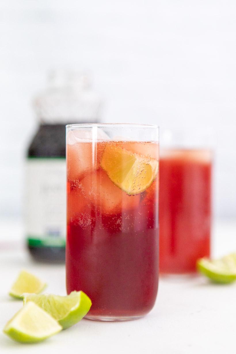 pomegranate lime spritzer in two glasses with ingredients in the background