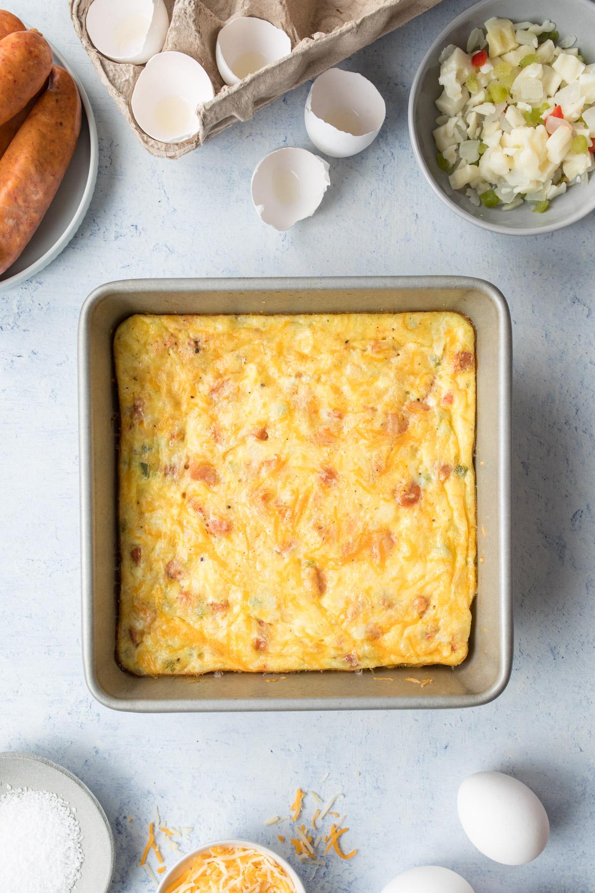 breakfast sausage casserole on plate with fried potatoes next to casserole in glass dish