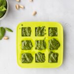 pistachio pesto sauce in ice tray with ingredients surrounding it