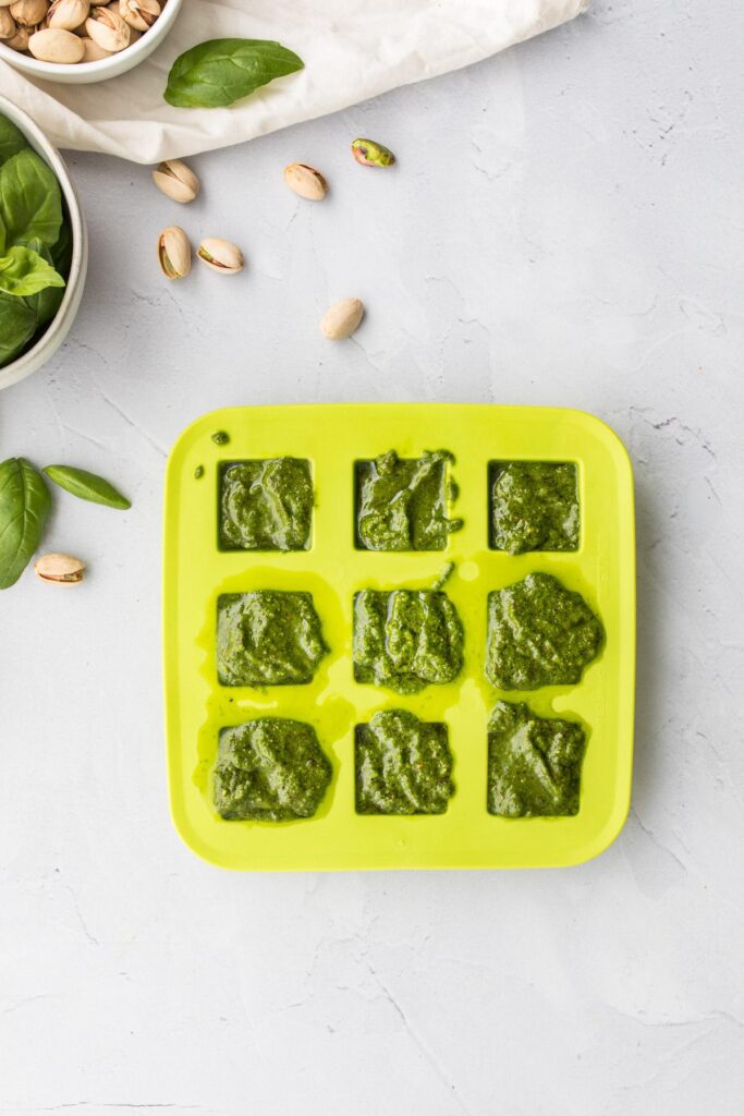 pistachio pesto sauce in ice tray with ingredients surrounding it