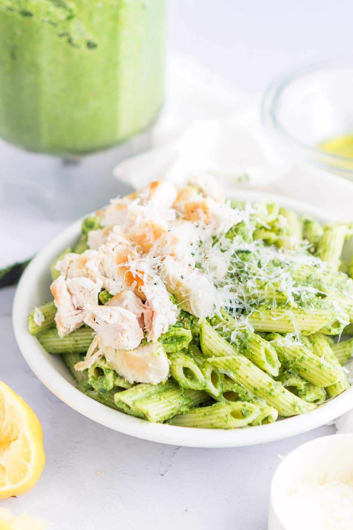 pasta pesto, chicken, and parmesan cheese in a white bowl