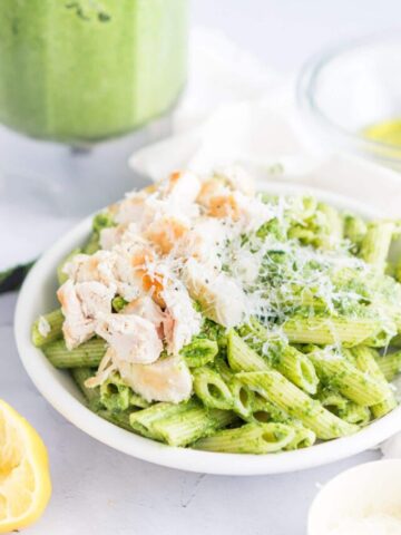 pistachio pasta with chicken and parmesan cheese in a white bowl