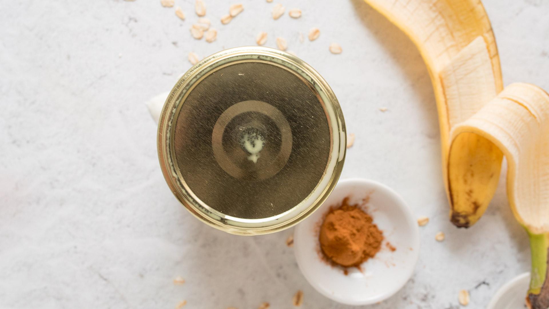 jar with a gold lid with a dish of cinnamon and a banana next to it