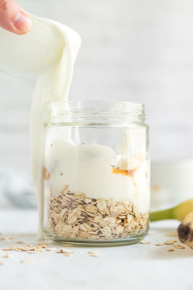 sliced banana in peel next to overnight oats in a jar