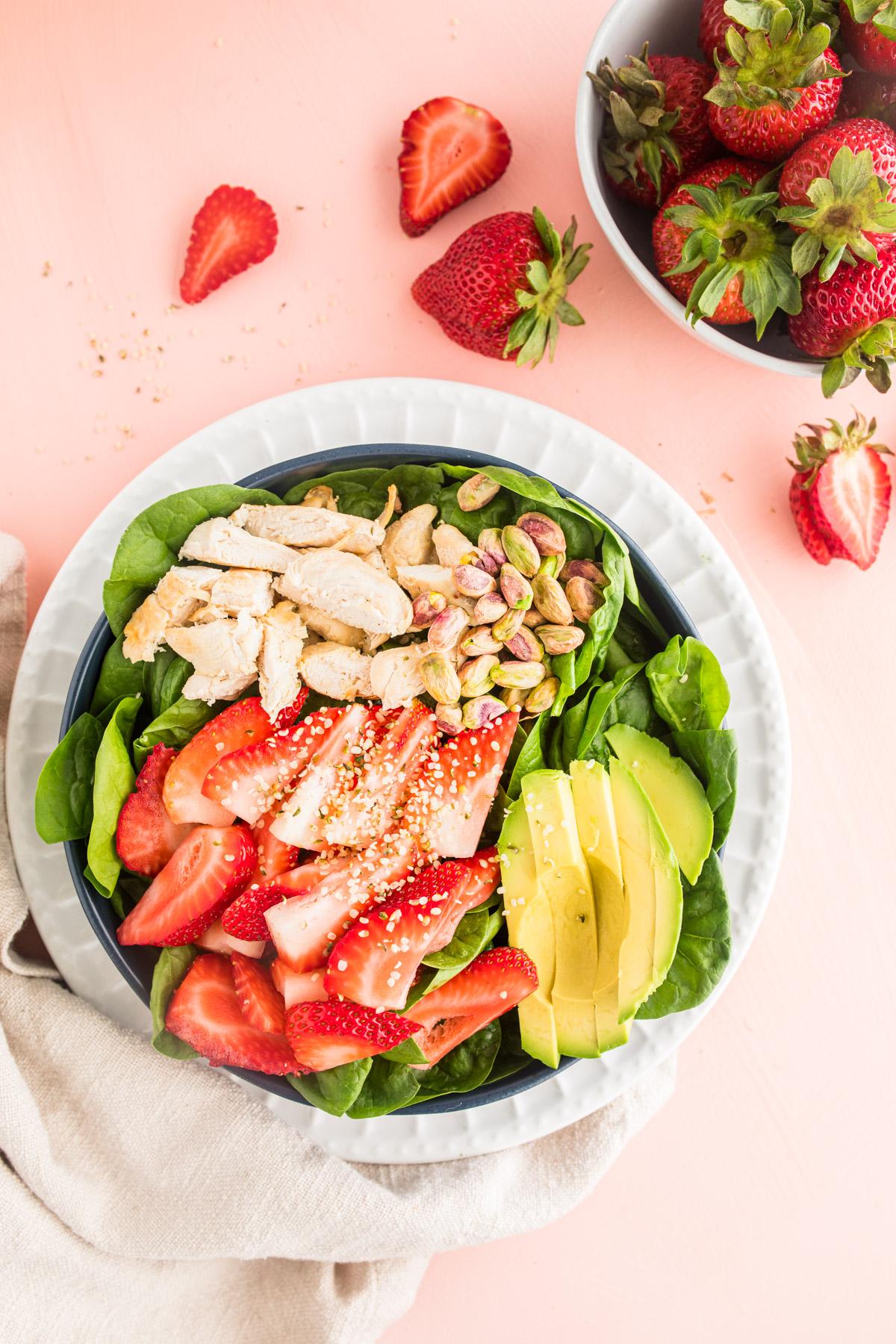 strawberry salad with chicken in bowl, with strawberries beside it
