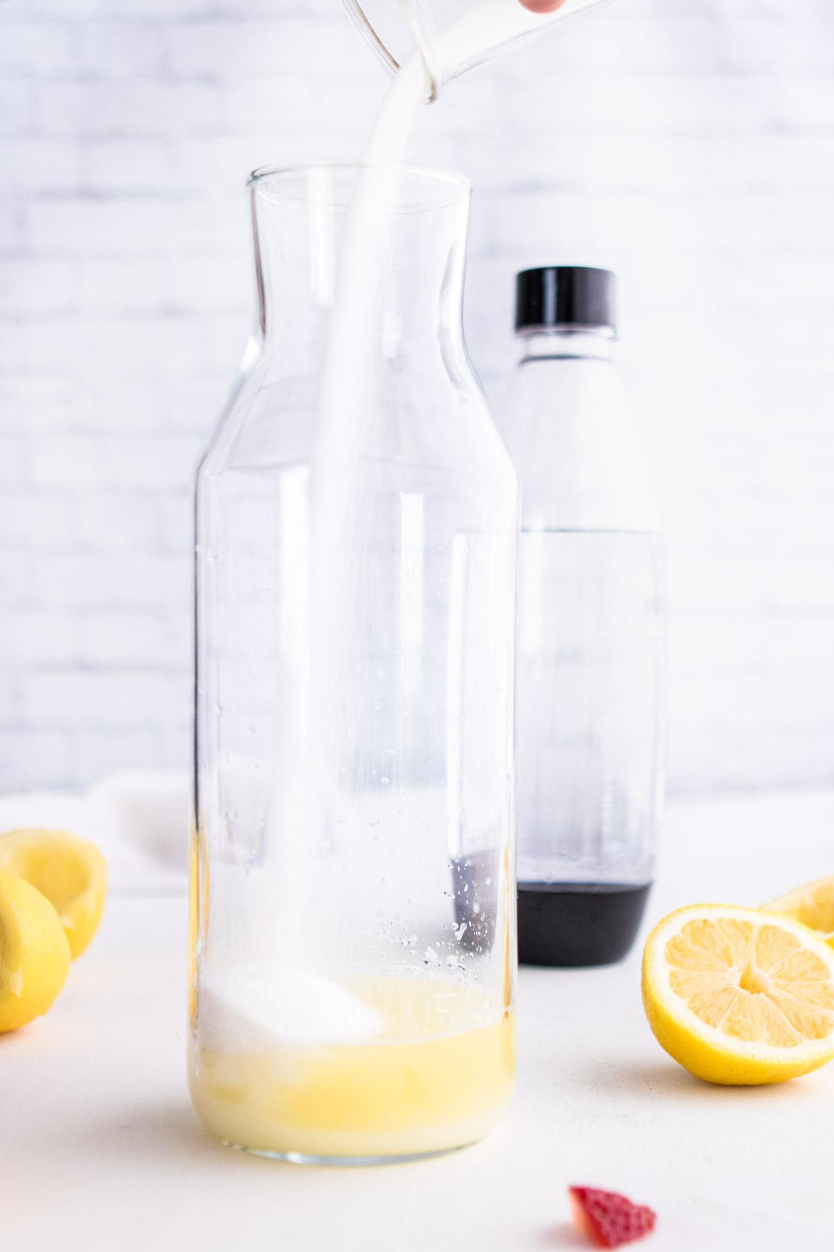 pouring sugar into carafe for sparkling berry lemonade