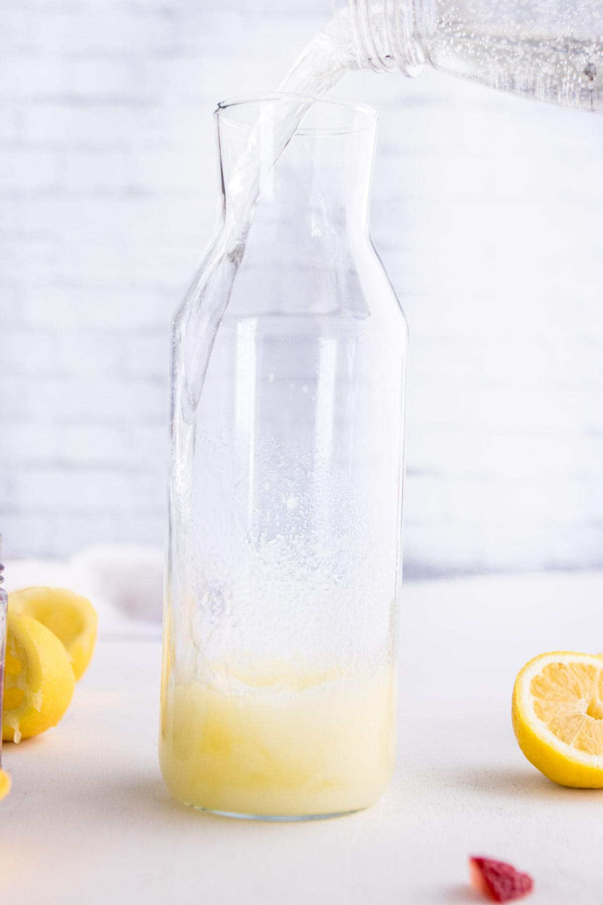 pouring sparkling water into a carafe with sugar and lemon juice