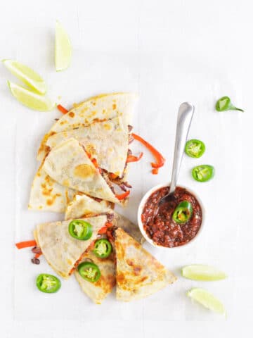 black bean & vegetable quesadilla on table with salsa and toppings