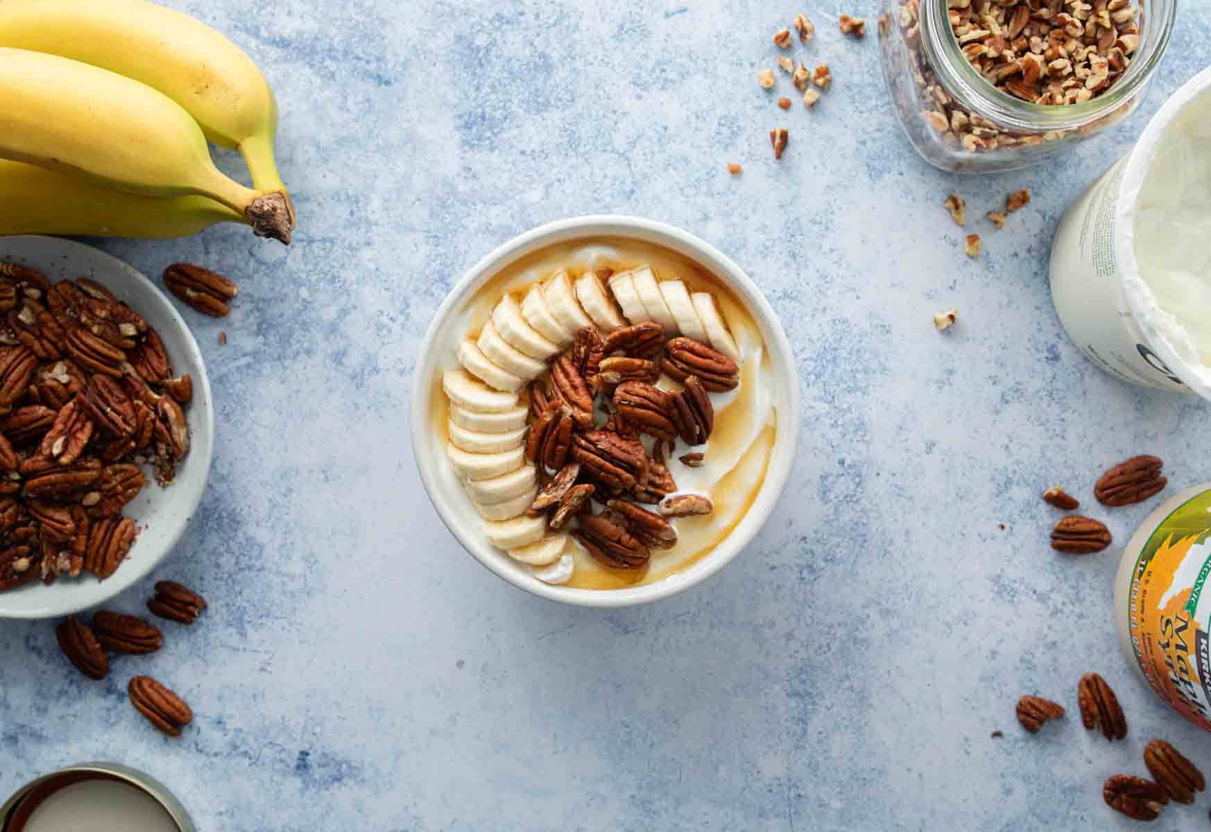 yogurt, banana slices, pecans, and syrup in bowl