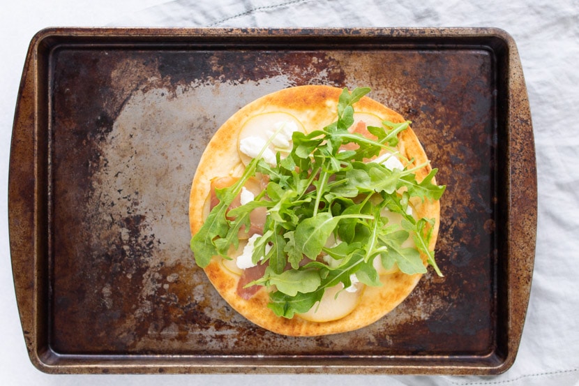 cooked pear prosciutto and arugula flatbread on pan