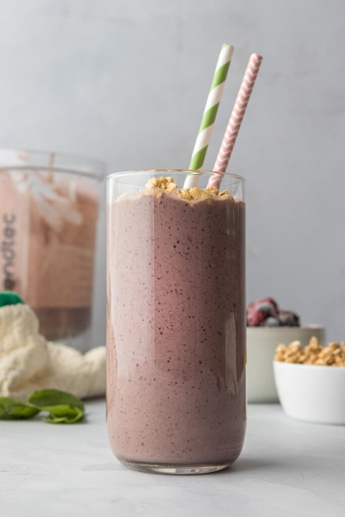 triple berry smoothie with granola with ingredients in background