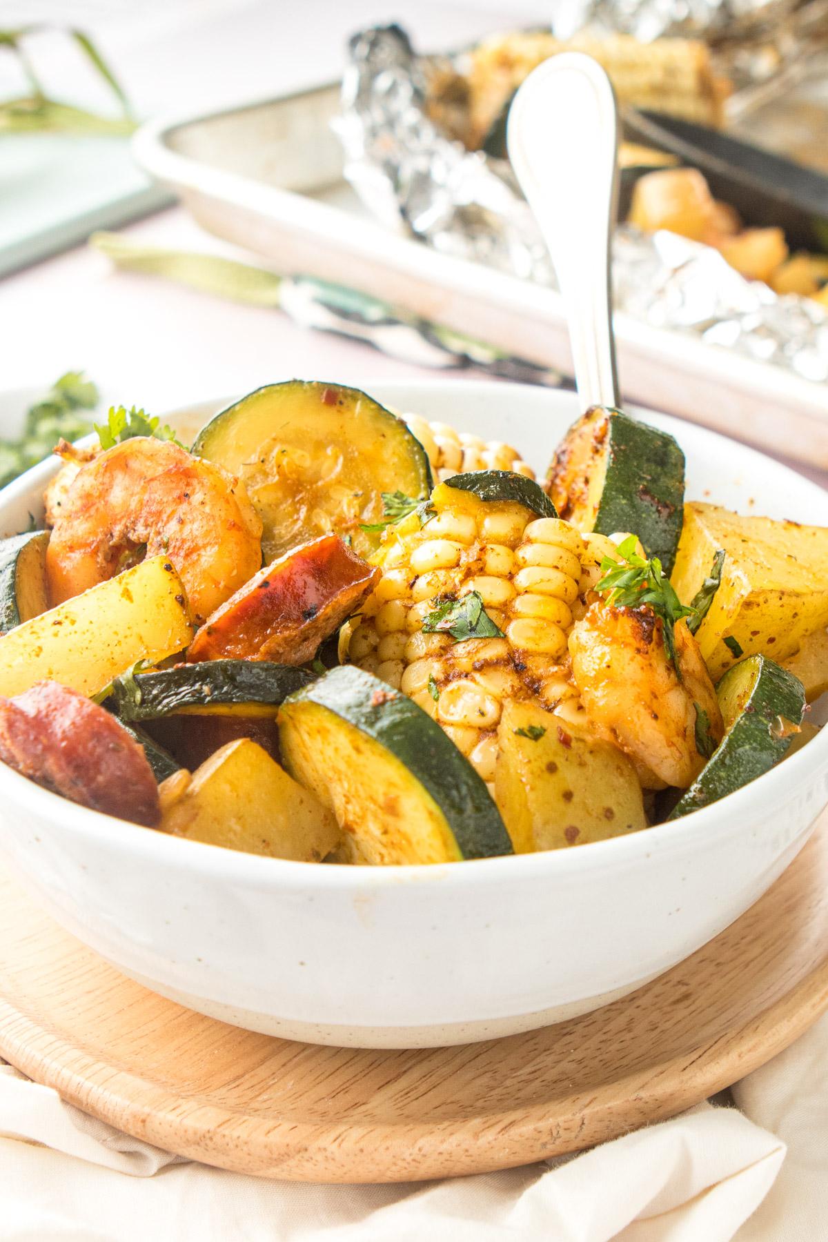 cajun shrimp & vegetable tin foil packets with oven mitt in background