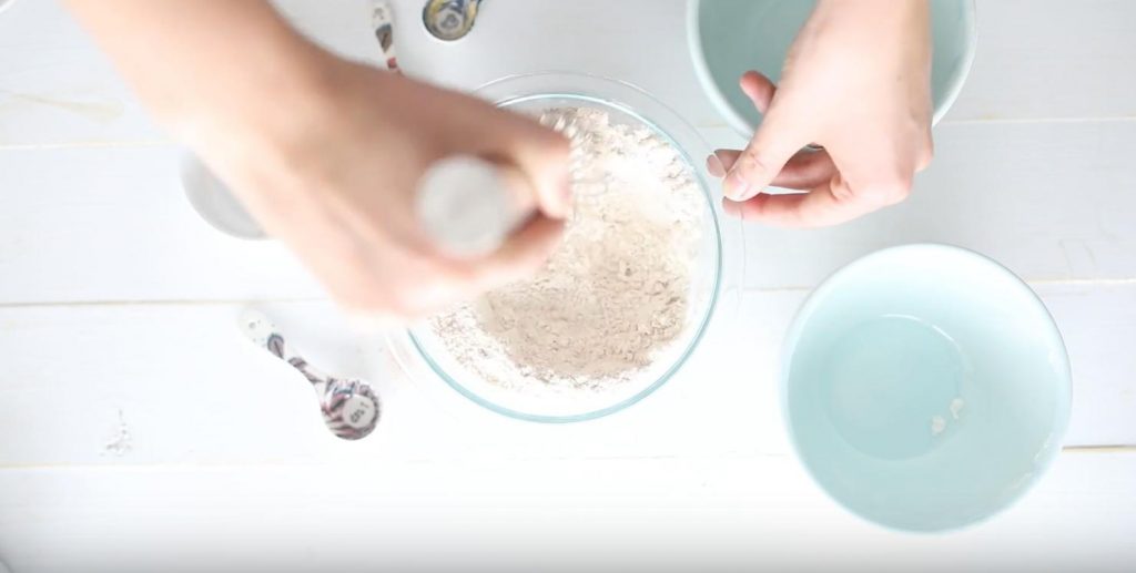 hand whisking flours in a glass bowl