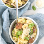 sausage and artichoke tortellini in bowl with garnishes on table