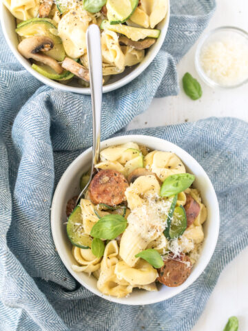 sausage and artichoke tortellini in bowl with garnishes on table