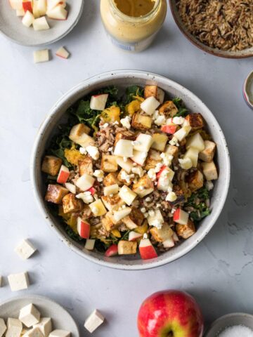 warm harvest bowl with apples and squash with wild rice and barley on table