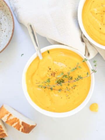 bowl of sweet potato soup with thyme garnish