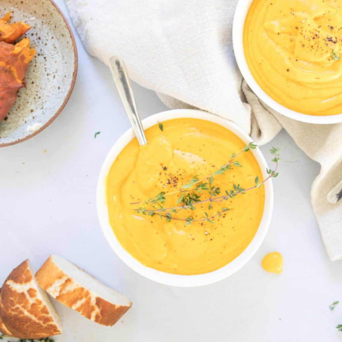 bowl of sweet potato soup with thyme garnish