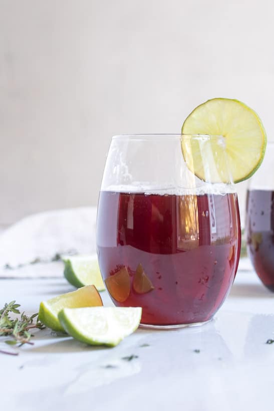 tart cherry spritzer in cup with limes on table