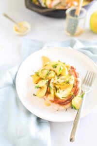 skillet pork chops with apples and vegetables on a white plate