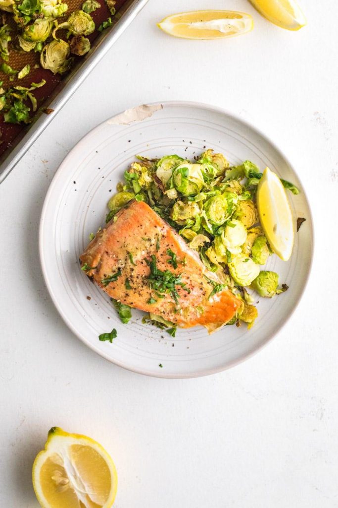 maple mustard salmon and brussels sprouts with a lemon wedge on a plate