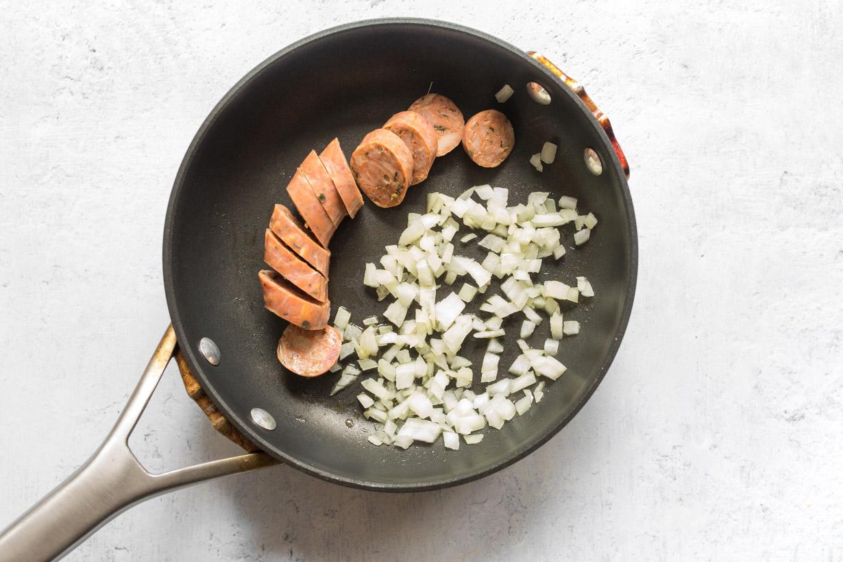 sliced sausage and chopped onion in a small frypan