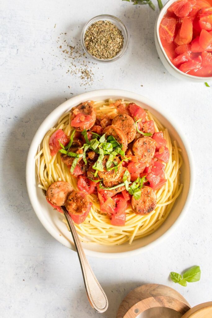 simple pasta in a white bowl with ingredients surrounding it