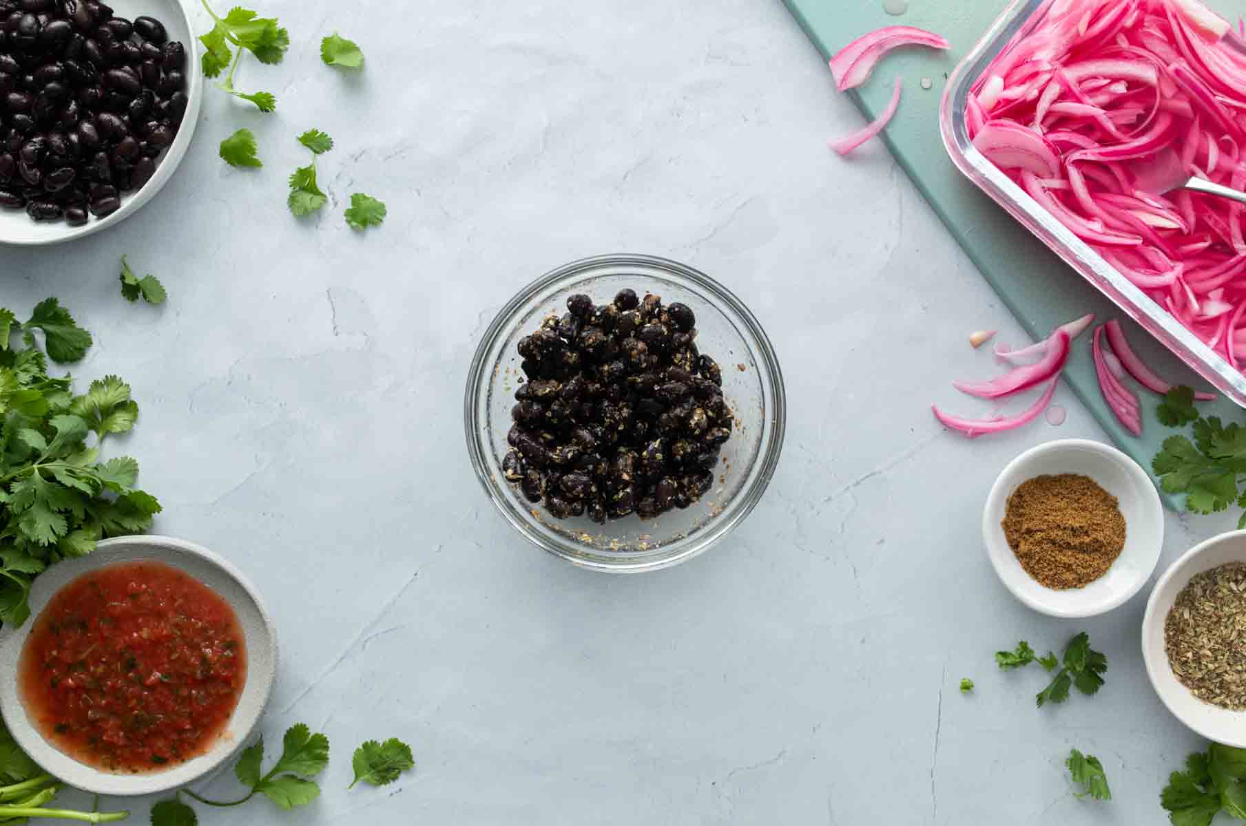 bowl of black beans with ingredients surrounding it