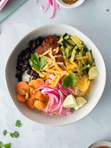 square image of burrito bowl with veggies on top