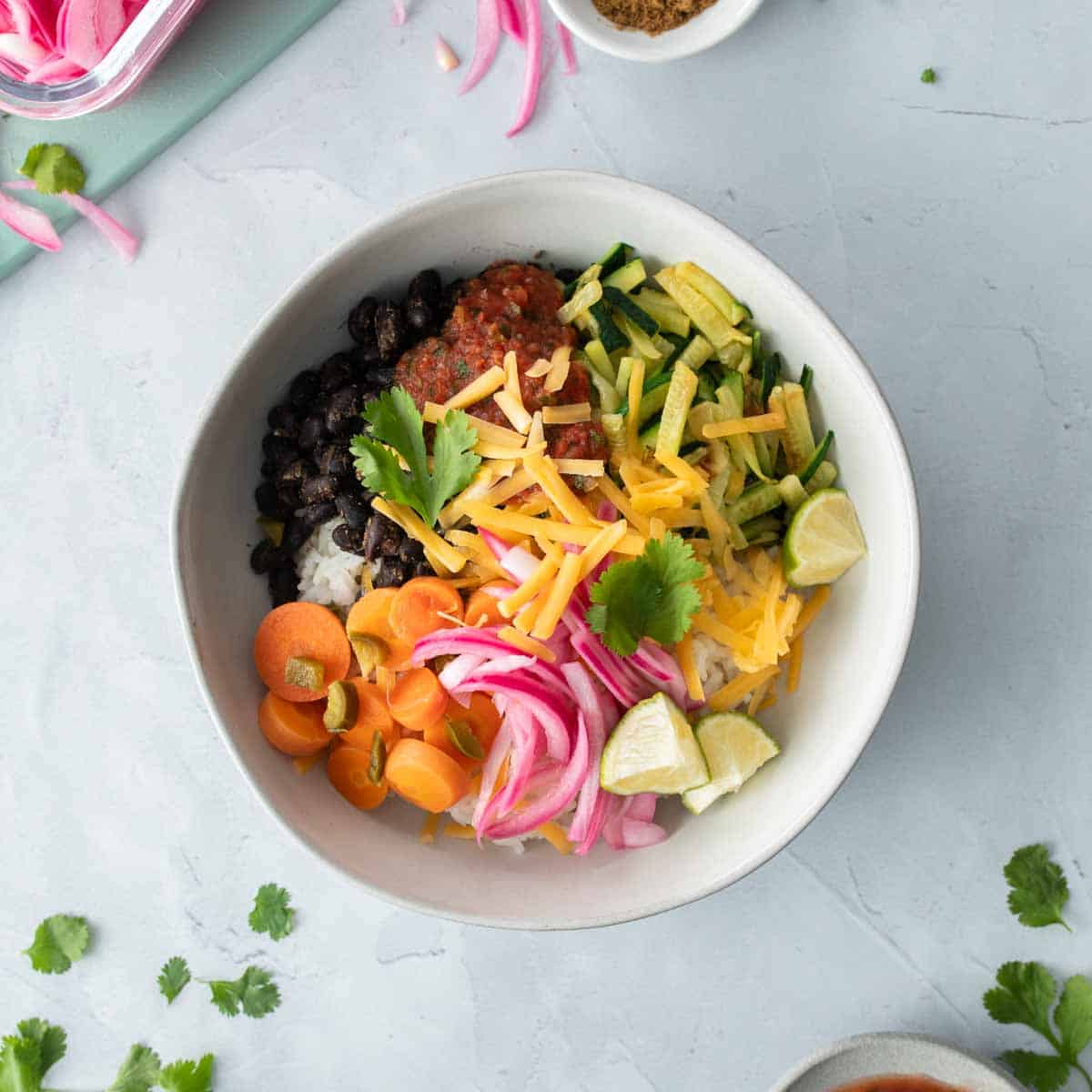 square image of burrito bowl with veggies on top