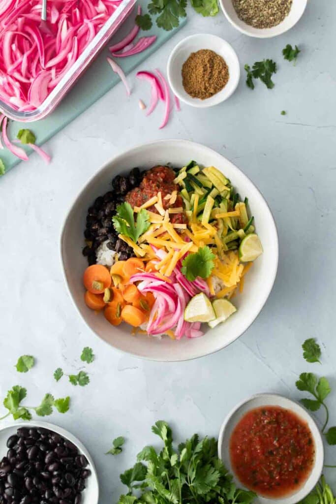 vegetarian burrito bowl recipe with queso in a bowl with other ingredients on a table