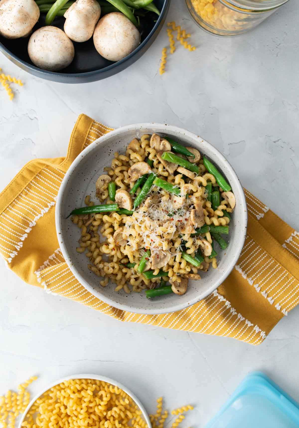 pasta with mushroom sauce in a bowl with other ingredients next to it on a table