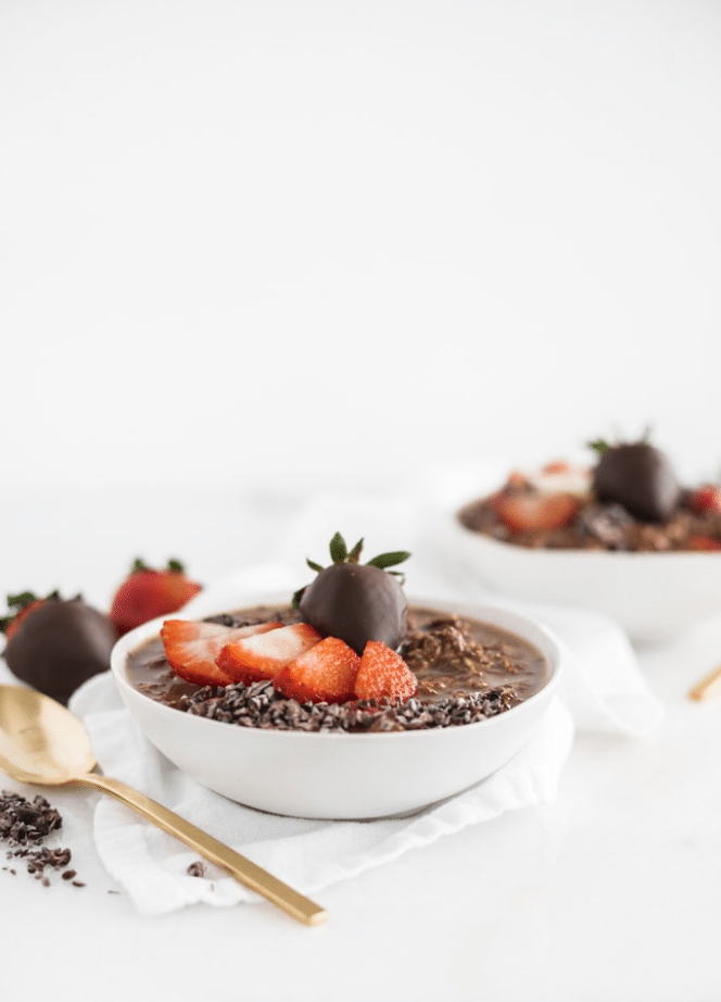 chocolate oatmeal in a white bowl with strawberries on top